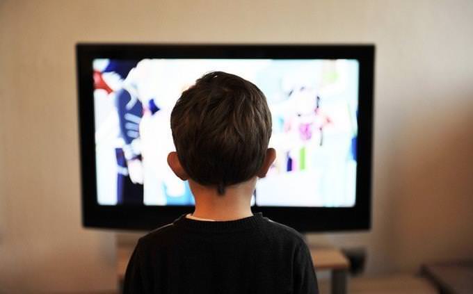 Um menino sentado na frente à TV