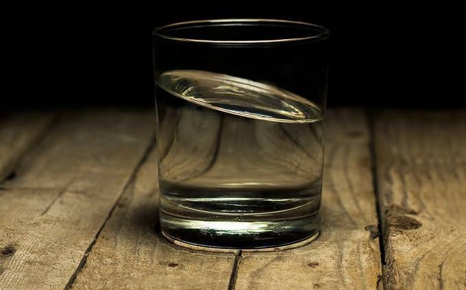 Um copo de água sobre uma mesa de madeira