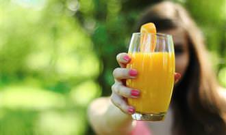 mulher segura copo de suco de laranja