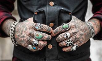 Jogos dos Erros: Mão tatuada de um homem com anéis
