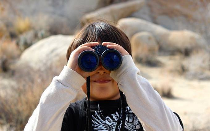 Um menino segurando binóculos na frente de seus olhos