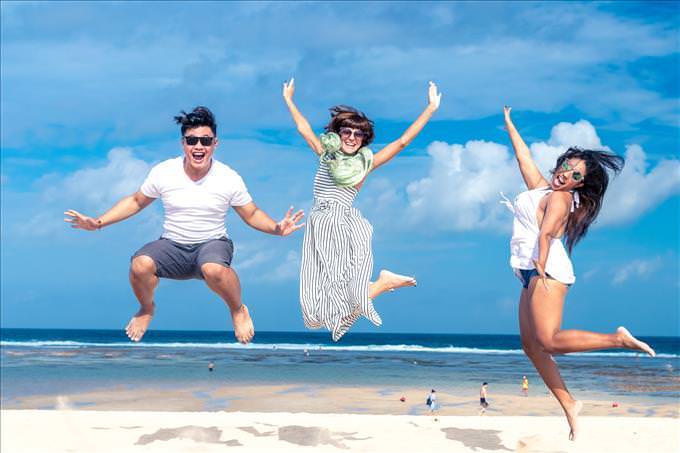 Jovens adultos pulando na praia