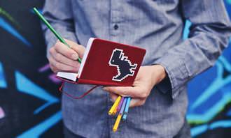Jogo dos Erros: homem segurando cadernos e lápis de cor