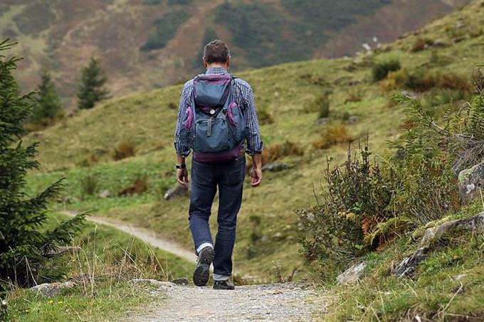 Um homem andando nas montanhas com uma mochila nas costas
