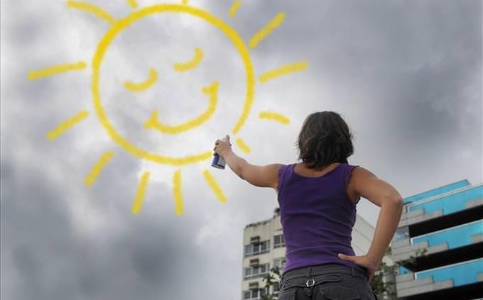 woman spraying sun over dark clouds