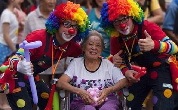 Two clowns making an older woman happy