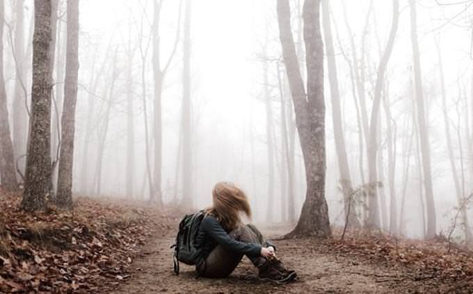 A girl with a backpack in the middle of a forest