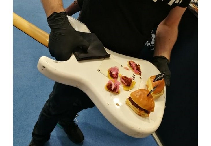 Hambúrguer vegetariano e nachos na parte de trás de uma guitarra elétrica