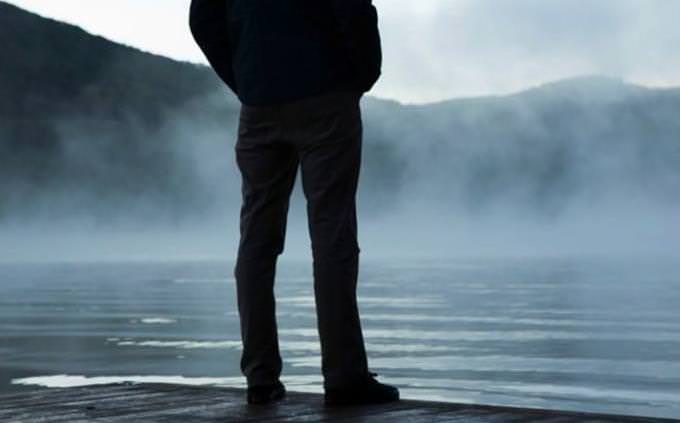 Homem parado na beira de um lago
