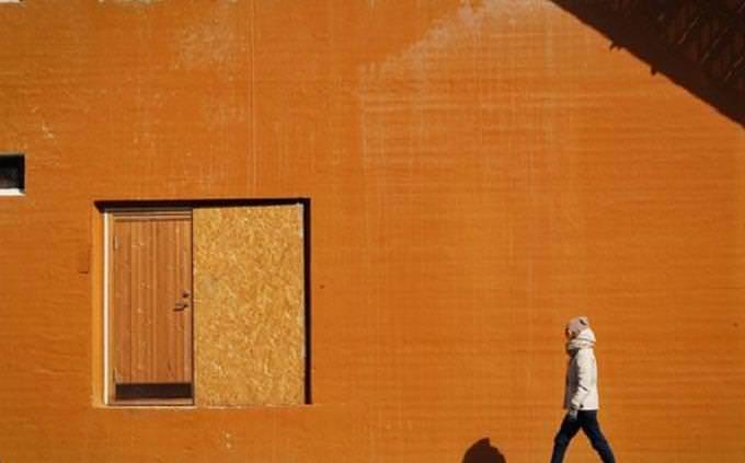 Homem andando perto da parede de laranja