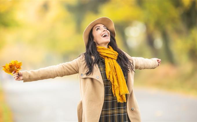 Encontre as diferenças no outono: uma mulher com roupas outonais levanta os braços para os lados
