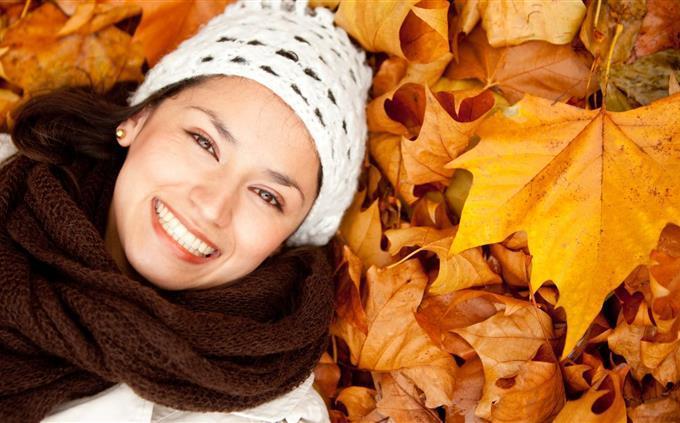 Encontre as diferenças no outono: uma mulher sorridente deitada nas folhas caídas