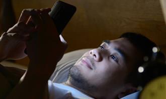 O que a rotina matinal revela sobre a personalidade: um homem na cama com um telefone