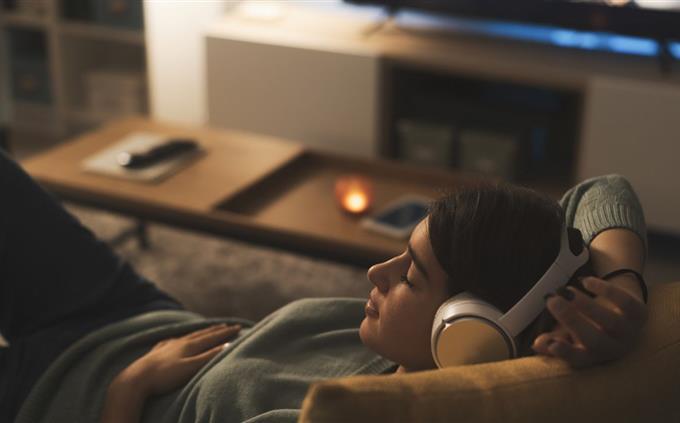 O que seus hábitos de sono evidenciam sobre seu futuro: uma jovem dorme em um sofá com fones de ouvido
