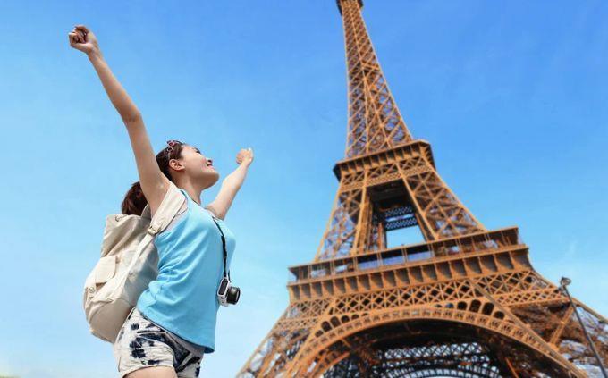 Curiosidades de costumes estranhos ao redor do mundo: Uma mulher feliz perto da Torre Eiffel