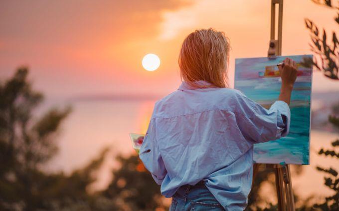 Qual planeta combina com sua personalidade: Mulher pintando em frente ao pôr do sol