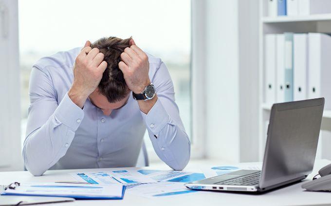 Você está cansado ou estressado: um homem na frente de um computador segurando a cabeça