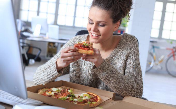 Você está cansado ou estressado: Mulher comendo pizza no escritório