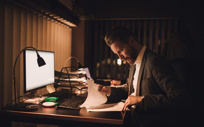 Você está cansado ou estressado: um homem trabalha no escuro na frente de um computador
